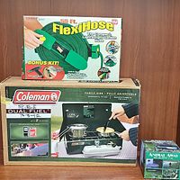 Photo showing the boxed Coleman Dual Fuel stove, boxed FlexiHose garden hose, and boxed Animal Away pest repellent.