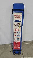 Photo shows the blue wheeled carry bag with label indicating 10ft x 10ft gazebo size, dimensions, and assembly instructions.
