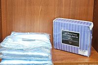 Two packaged sheet sets side by side with one blue satin folded sheet set and one in original packaging labeled 340 Thread Count 100% Cotton Sheet Set Full Size.