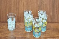 One vintage Anchor Hocking glass tumbler with colonial design shown next to five Mid-Century glass tumblers with tri-color leaf designs.