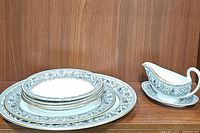 Stack of three oval vegetable dishes and two platters on left, gravy boat with underplate on right