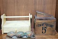 Photo of vintage wooden shoe shine box, wooden paper towel caddy, and teak wood condiment set on shelf.