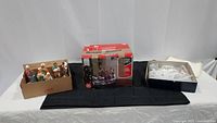 Wide shot showing two boxes of ceramic nativity figurines and boxed Christmas Village piece