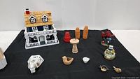 Image showing full collection including large shingled birdhouse, mini terra cotta pots, bird figurines, ceramic night light and other decorative items on black cloth