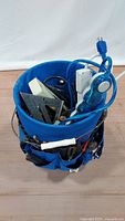 Top-down view of bucket showing contents including electrical cords and small hand tools