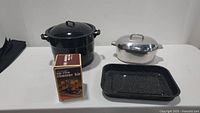 Wide view of the lot showing all items: Granite Ware canning pot with lid, Wagner Ware oval roaster with lid, rectangular roasting pan, and Upside Roaster Kit box.