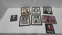 Eight signed photos laid flat on a white surface, some framed and some not, featuring various famous people.