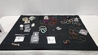 Wide shot showing entire assortment of costume bracelets laid on black cloth, various colors and styles visible, some packaged.