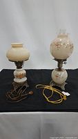 Photo of two vintage glass globe lamps side by side showing differences in size and floral decoration.