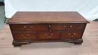 Front view of Lane cedar chest with brass handles and lock, wooden polished top and base.