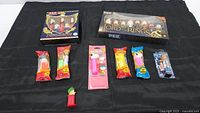 Wide view of all Pez dispensers included in the lot, showing the boxed sets and individual dispensers on black cloth.