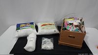 Collection of stuffing materials with two sealed polyester fiber pillows and various trim supplies including elastic, bias tape, and velcro in a box.
