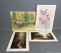 Four watercolor paintings displayed together showing various landscapes and a floral still life.