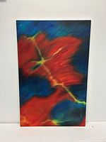 Front view of abstract oil painting featuring large red areas with blue and yellow-green accents on canvas