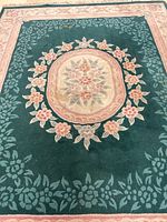 Close-up of central medallion and floral wreath design on deep green background.