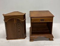 Corner cupboard with double doors and stand with drawer against white backdrop.