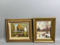 Two framed landscape oil paintings side by side on a neutral wall, one depicting an autumn scene and the other a winter scene.