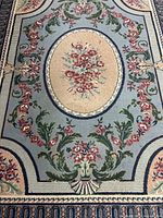 Close-up photo of the central floral oval and surrounding leafy and floral patterns on rug.