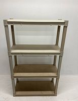 Front view of four-tier beige plastic shelf unit, showing flat shelves and vertical support posts.