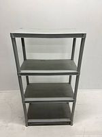 Front view of portable plastic shelf unit showing four shelves and tubular legs.