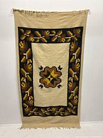 Full view of the tapestry hanging on a white wall showing the entire pattern and fringe details