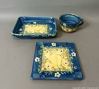 Set including rectangular dish, square plate, and cup showing hand-painted floral design with blue border