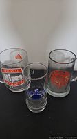 Three glass mugs placed on black surface: Original Hires Root Beer mug, Ottawa Technical High School mug with orange logo, and a third mug with red Ottawa Tech logo