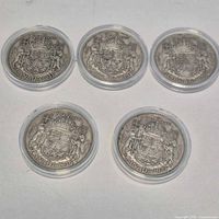 Five Canadian 50-cent coins dated 1943-1947 in capsules