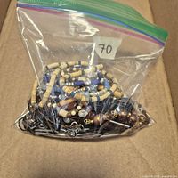 Ziploc bag filled with assorted beaded jewelry pieces inside cardboard box