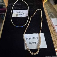 Both necklaces displayed on black surface showing overall appearance