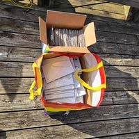 Bag containing numerous individually sleeved jewelry pieces and a cardboard box inside