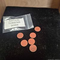 Plastic bag labelled Ration Tokens WWII and six red OPA tokens on black background