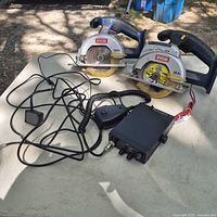 Both Ryobi saws, radio with microphone, wiring and adapter on table