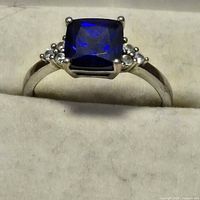 Close-up of sterling silver ring with square blue stone and side accents