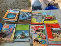 Stacks of assorted vintage automotive magazines on table