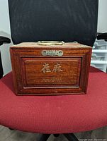 Front view of closed wooden box with metal handle and decorative inlays