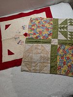 Two handmade baby doll quilts spread on a white textured surface. The quilt on the left shows a red border and a circular applique pattern in the center. The quilt on the right shows patchwork with floral and green fabric squares.