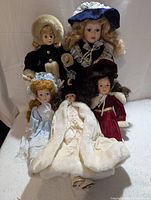 Overview of five porcelain dolls grouped together showing details of clothing and hair