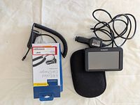 Garmin GPS device with car charger and protective pouch laid out on table