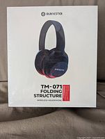 Front view of sealed box showing Burnester branding and TM-071 model with folding structure wireless headphones image.