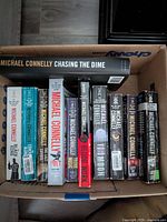 Box of 10 Michael Connelly books arranged upright showing titles on spine including 'Chasing the Dime','The Poet','Blood Work', among others.