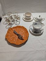 Photo of the entire lot showing cheese plate, spreader, juice glasses, cups, saucers, and sugar bowl