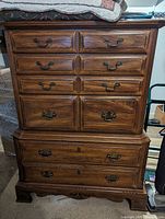 Full frontal view of the oak chest of drawers showing all drawers and brass handles.