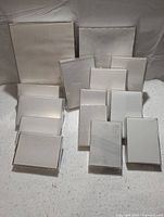 Set of 13 clear plastic picture frames with white paper inserts on light fabric surface.