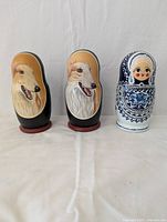 Photo showing two largest dog portrait nesting dolls and one traditional blue and white floral nesting doll, illustrating different art styles and sizes.