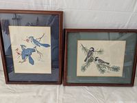 Photo of two framed Sherm Pehrson bird paintings, one with blue jays, one with chickadees.