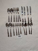 Full view of 20-piece silver plated flatware set including 4 dinner knives, 4 dinner forks, 4 salad forks, 4 tablespoons, and 4 teaspoons arranged on a light surface.