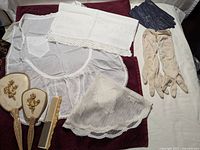Lot items displayed flat, including apron, table scarves, gloves, and comb and brush set.