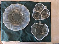 Large textured vintage glass plate, three-compartment candy dish and heart-shaped candy dish shown on green fabric placemat