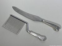 Two vintage sterling silver serving utensils, cake rake and carving knife, showing overall condition and design details.